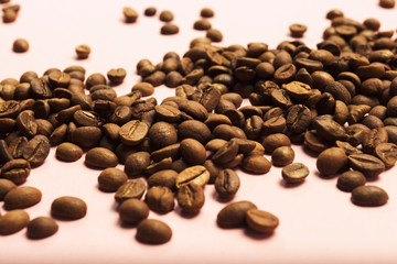 Coffee grains on a gently pink background. Flat lay, top view