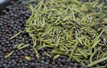 Dry rosemary with black mustard seeds closeup. Spices background. Organic healthy food. Cuisine and cooking concept. Herbs in the kitchen. Aroma herbs and spices. Black pepper seeds with rosemary. 