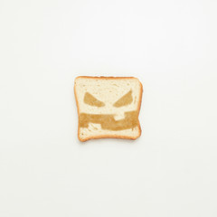 Slice of toast with an evil smile on a white background.
