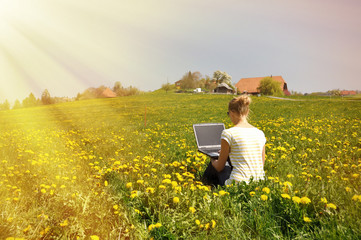 Girl with a notebook computer on the spring meadow