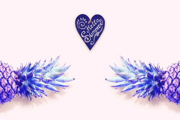 Creative concept with pineapple and heart with the inscription "Hello summer." The top of the pineapple is colored gradient. Flat lay, top view, copy space. Minimum summer concept.