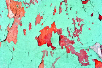 Cracked soft turquoise paint, plaster surface on red wall, grunge horizontal shabby background detail close up