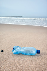 Fototapeta na wymiar Plastic bottle left on a beach, selective focus, color toning applied.