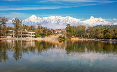 Fototapeta na wymiar Scenic landscape view of a small village town with adjoining lake at Bageshwar district Uttarakhand with full panoramic view of the Garhwal Himalaya range.