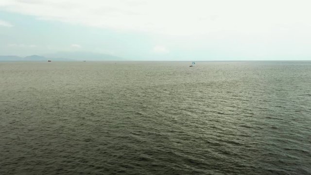 Moving drone shot above an open sea off the coast of Bali, Indonesia. Boats in the distance.