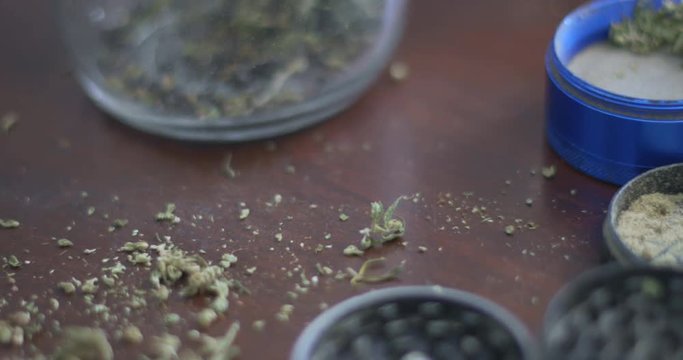 Marijuana grinders filled with weed and kief on a wood background. Pan right.