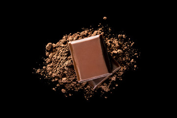 Piece of chocolate bar with heap of cocoa powder on black. Top view.