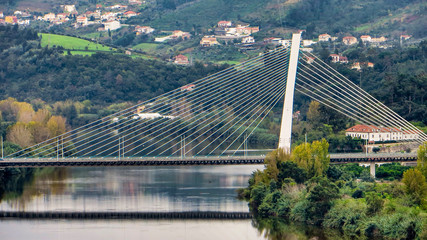 Bridge over the river that flows below the University at Coimbra Portugal with rolling hills, houses and trees in the background.