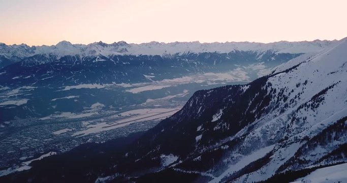 Innsbruck, Austria - view over city Innsbruck in the valley with snowy Alps during sunset | Aerial View