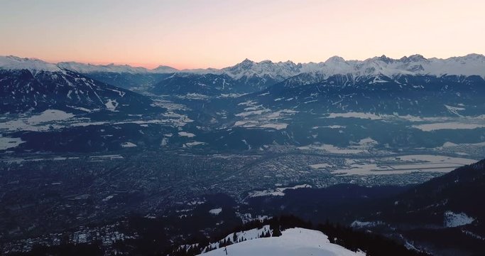 Innsbruck, Austria - view over city Innsbruck in the valley and Inntal Autobahn with snowy Alps during sunset | Aerial View