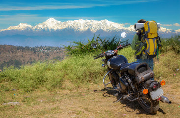 Tourist backpacker with his bike admires the majestic Himalaya mountain range at Uttarakhand India.