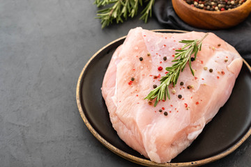 Turkey breast raw meat with spices on a dark background. Copy space.