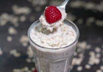 Haferflocken als Overnight Oats mit Himbeere im Glas beim Essen auf Löffel