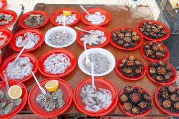Open air street food fish market on Bari promenade with raw fresh sushi ready to eat: shrimp, oyster, sea urchin, cuttlefish, squid, octopus and various fish with lemon