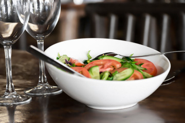 Traditional Mediterranean food. Two glasses and dish with fresh sliced vegetables on the table in the restaurant. Salad with tomatoes and cucumbers.