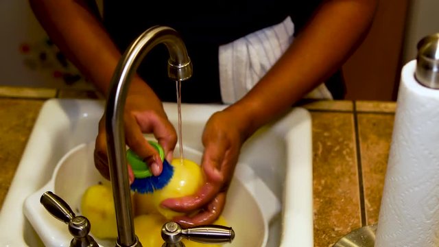 Close Up, Woman cleaning golden yellow apple with scrub brush