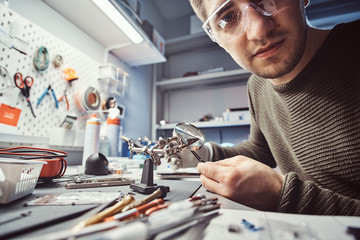 Electronic technician working in the modern repair shop, looking at a camera