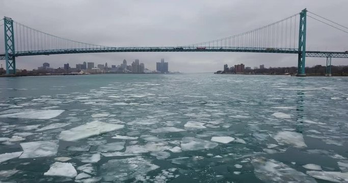 Trucks driving over large ice chunks floating under the Ambassador Bridge in the Detroit River.