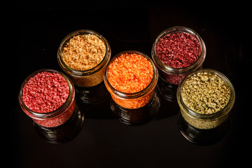 top view of small glass jars filled with different colors sea salt