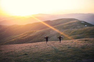 two girls in a black sweater run together to meet the sun