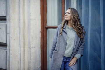 Fototapeta premium Fashion model wearing ripped boyfriend jeans, jacket and sneakers posing in the city