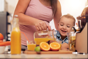 Obraz na płótnie Canvas Son helping mother to prepare juice