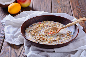 Healthy and tasty breakfast made from muesli with fruit pieces is being filled with milk