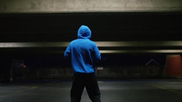 Hooded male in a sweater warming up and stretching his arms