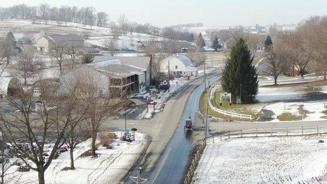 Following buggy driving over road in Amish town. Shot in Intercourse, Pennsylvania in wintertime. A beautiful snow covered rural town with farms, meadows, farmlands and a small village center.