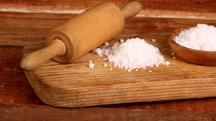 Salt or sea salt and rolling pin on a aged wooden table background.