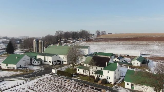 Slowly flying over farm with silo's in rural area. Shot in Intercourse, Pennsylvania in wintertime. A beautiful snow covered town with farms, meadows, farmlands and a small village center.