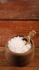 Salt or sea salt in a wooden bowl on a aged wooden table background.
