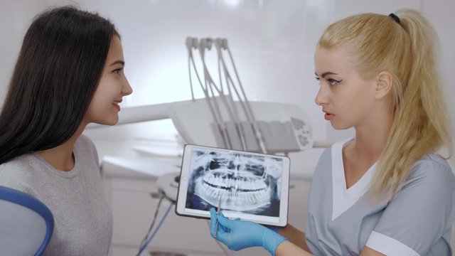 Dentist and patient choosing treatment in a consultation with medical equipment in the background