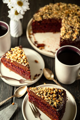 Homemade cake covered with chocolate icing and walnuts cut into slices and tea. High angle shooting, selective focus.
