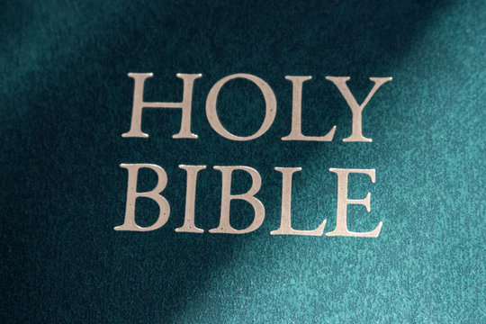 Holy Bible title closeup in sunlight. Religion and faith concept. Religious literature. Bible isolated. Christianity background. Vintage Bible book in light.