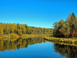 Autumn landscape of Gauja river valley and colorful forest reflecting in mirror water