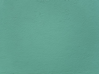 Rough mint green painted wall, stucco texture.