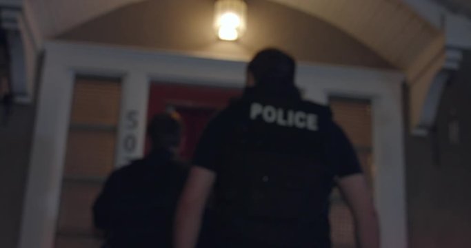 Police officers approach a house