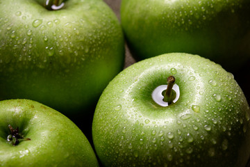 green apples with drops on dark background