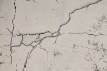 Cracked old wall with peeling white paint and dirt
