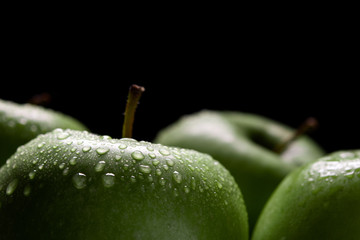 green apples with drops on dark background