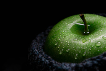 lonely green apple with water drops in a woolen bag