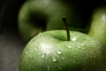 green apples with drops on dark background