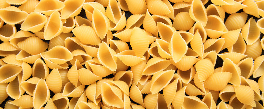 Uncooked macaroni shell shape pasta texture background, banner