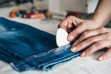Obraz na płótnie Canvas Seamstress marking hem on a pair of jeans in tailor shop