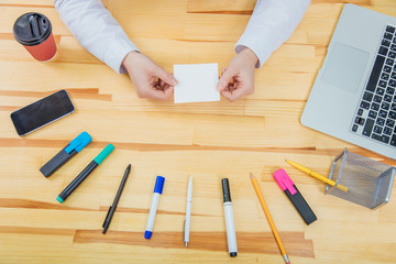 Office table with accessories: white paper, blue and pink marker, black phone, coffee cup, pen, pencil.Hold a white sheet of paper.