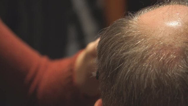 Woman Hairdresser cuts man's hair with electric clipper trimmer. Selective focus