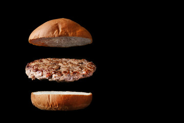 flying burger with bun and patty isolated on black background