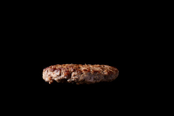 floating grilled burger patty isolated black background