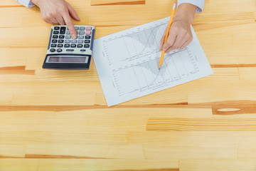 Businesswoman analyzing investment charts with calculator for financial data analyzing counting.